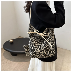 Close-up of leopard print tote bag with beige bow accent on a stylish fabric surface