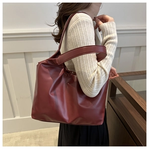 Elegant burgundy oversized tote bag in glossy leather look worn over the shoulder