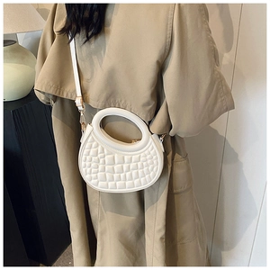 Close-up of beige dumpling bag in embossed texture with champagne gold hardware