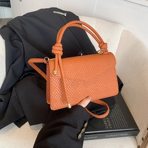 Brown woven leather crossbody bag with knot handle on elegant dark blazer