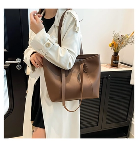 Grand sac cabas marron en similicuir avec texte embossé porté sur un trench blanc