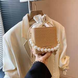 Beige woven bucket bag with pearl handle and gold chain strap in minimalist square style