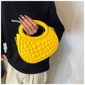 Detail of a bright yellow crescent handbag with embossed 3D grid texture and ring handle