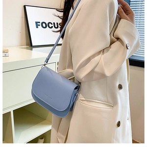 Detail of light blue leather saddle bag with adjustable strap worn by a model