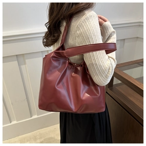 Detailed side view of dark red leather tote bag with wide strap and soft texture