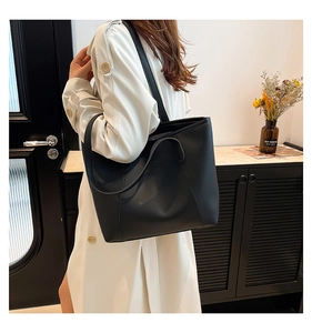 Vue latérale d'un grand cabas noir minimaliste en cuir porté comme sac à bandoulière