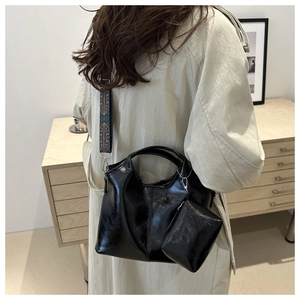 Dettaglio borsa tote in pelle PU nera con tracolla etnica e mini portamonete