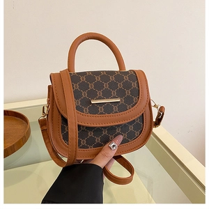 Detail of vintage saddle bag featuring retro pattern and gold metal bar buckle