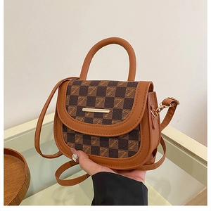 Detail shot of vintage brown saddle bag with checkered pattern and gold hardware
