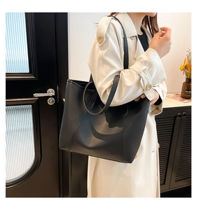 Grand cabas en cuir noir porté par un mannequin pour une tenue de bureau moderne