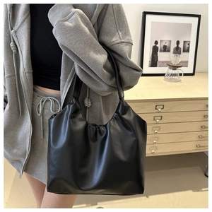 Close-up of minimalist black leather hobo tote bag with wide strap for daily commute