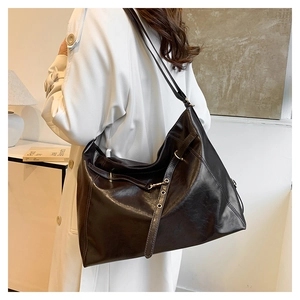 Detail of vintage brown leather tote bag with metallic buckle and stitching textures