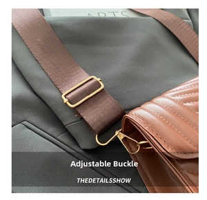 Detail of adjustable golden metal buckle and brown nylon strap on a quilted crossbody bag