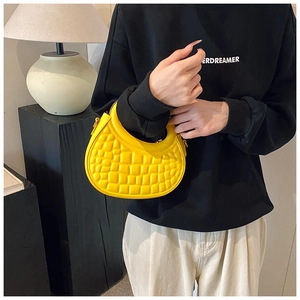 Detail of yellow embossed faux leather shoulder bag with sleek semicircular handle design