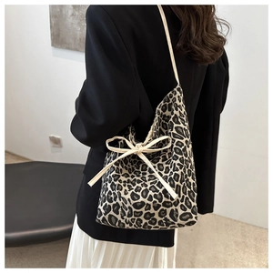 Detail of leopard print canvas tote bag featuring a large decorative cream bow on strap