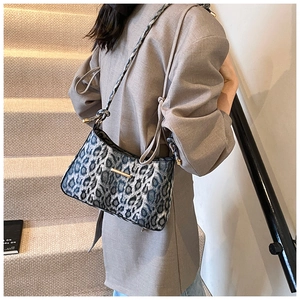Detailed view of leopard print hobo bag with gold metal trim worn by a model