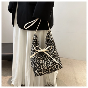 Detail der Damenhandtasche mit Leopardenmuster und dekorativer Schleife am Modell