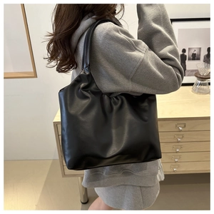 Close-up of black matte leather tote bag with soft texture and minimalist shoulder strap