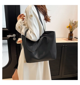 Détail d'un grand sac cabas en cuir noir à larges bandoulières porté par un mannequin