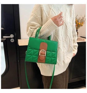 Détail du sac à main vert matelassé avec boucle dorée et lanière de cuir brun élégante