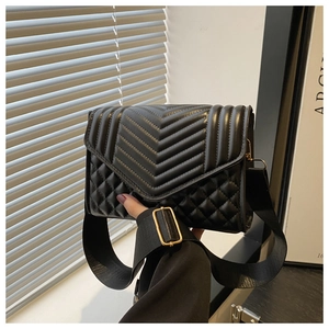 Detail of black quilted crossbody bag with chevron pattern and wide fabric strap