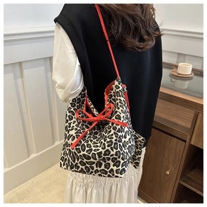Back view of model wearing leopard print bucket bag with red bow drawstring straps