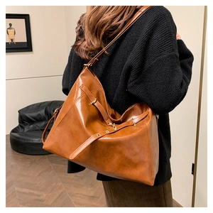 Detail view of a large brown vintage tote bag showing glossy leather texture and metal rings