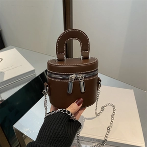 Deep brown cylindrical bucket bag with white contrast stitching and silver chain strap