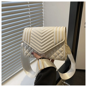 Close-up of white quilted crossbody bag with chevron pattern and wide nylon strap