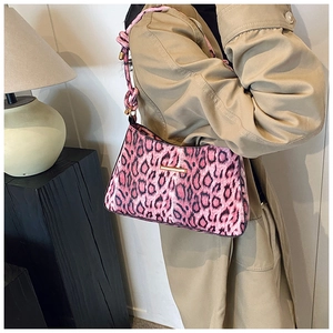 Detail of pink leopard print shoulder bag with knotted strap and gold hardware on model