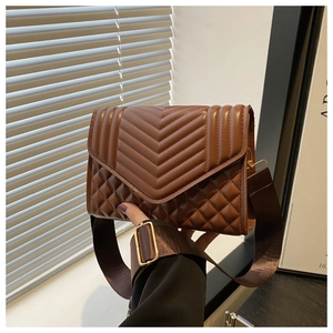 Detailed side view of a brown quilted crossbody bag with wide strap and gold hardware