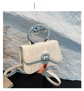 Detail view of white marble handbag with unique silver curved handle and metallic clasp