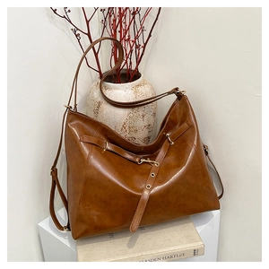 Detail of dark brown vintage leather tote with metallic hardware on a minimalist background