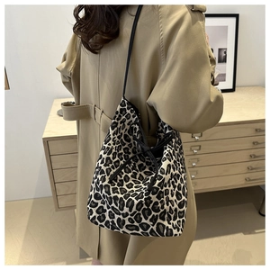 Leopard print drawstring tote bag with slim shoulder straps shown on model in a cozy setting