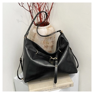 Detailed view of matte black leather bag with fine texture and metal buckle accents