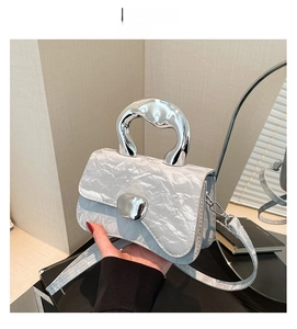Close-up of a silver handbag with metallic pleats and streamline metal handles