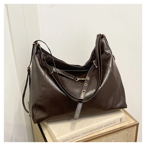 Detail of dark brown leather tote bag showing visible stitching and adjustable strap