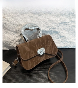 Close-up of coffee brown pleated leather bag featuring a unique silver metal handle