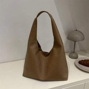 Sac fourre-tout marron en similicuir tressé au design hobo minimaliste sur une table