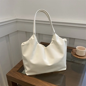 Minimalist large capacity tote bag in off-white faux leather shown in a lifestyle interior