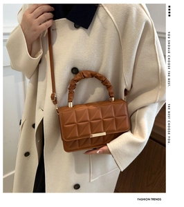 Detail of caramel quilted handbag featuring geometric stitching and ruched cloud handle