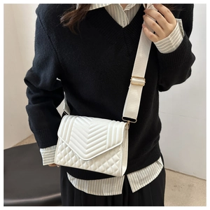 Detail of white quilted crossbody bag with gold hardware and wide adjustable strap
