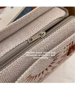 Detailed macro view of the smooth silver zipper and canvas texture on the beige tote bag