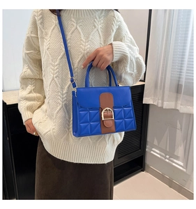 Detail der blauen gesteppten Handtasche mit braunem Riemen und goldener Schnalle