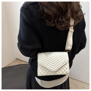 Detailed back view of model wearing white quilted crossbody bag with wide shoulder strap