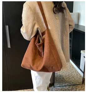 Detail of a large brown faux suede tote bag worn on shoulder for a stylish commuting look