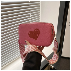 Pink faux leather crossbody camera bag with red heart and patterned wide canvas strap