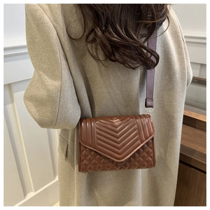 Close-up of brown quilted crossbody bag featuring V-shaped and diamond stitching textures
