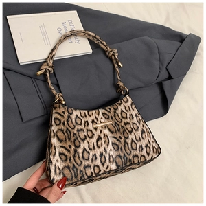 Detail of leopard print handbag with golden metal bar and knotted shoulder strap