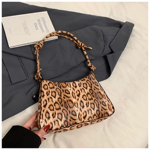 Close-up of leopard print underarm bag with unique knotted handle on a gray blazer
